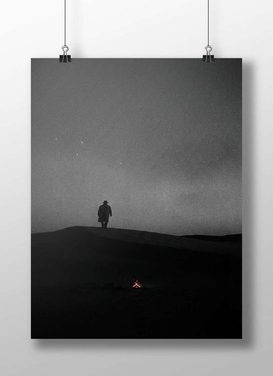 A lone human silhouette standing atop a sand dune under a starry night sky Main Subject: A lone human silhouette standing