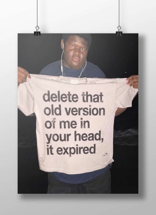 The phrase "delete that old version of me in your head, it expired" printed on a T-shirt. Main Subject: The phrase "delete