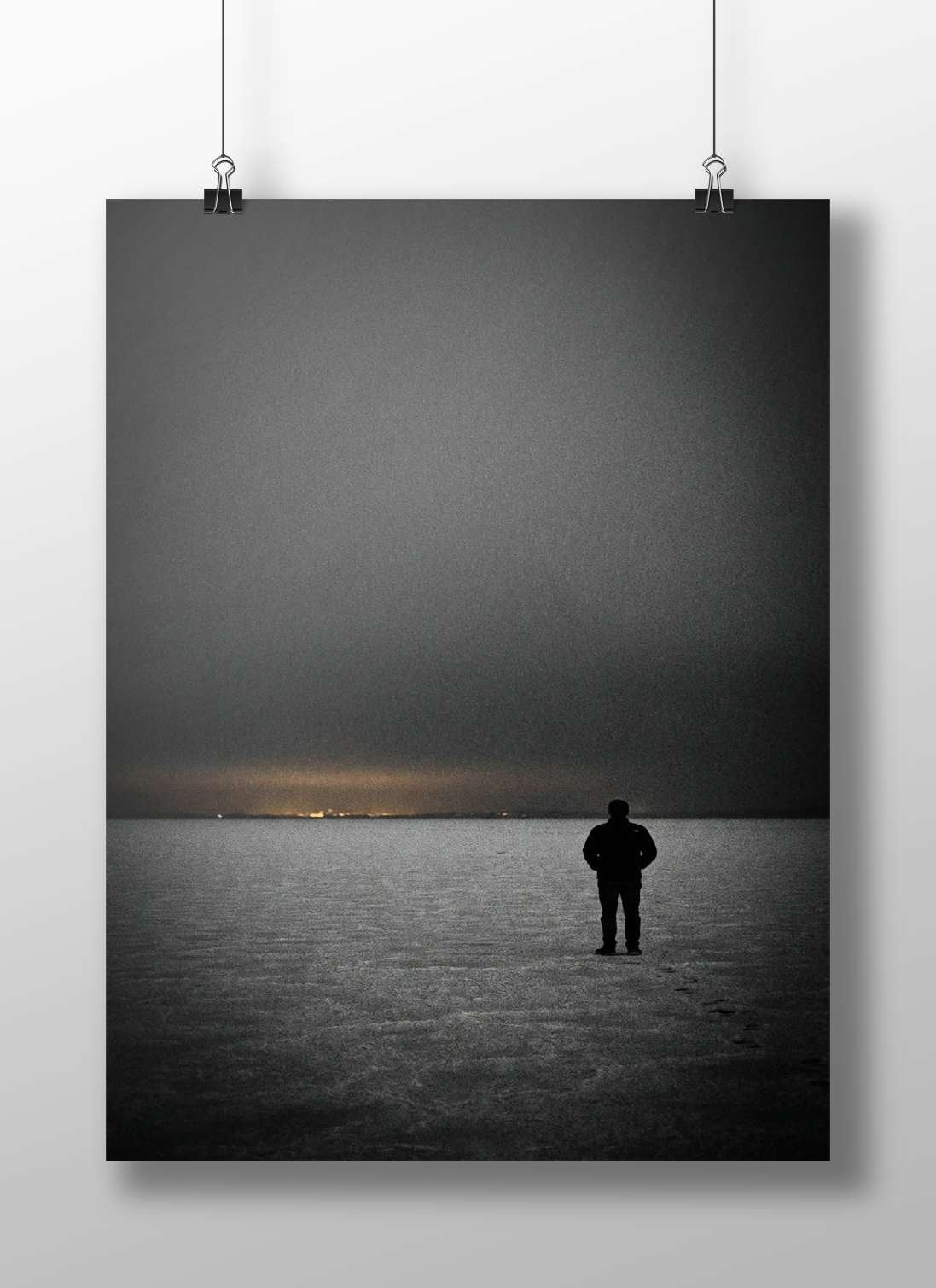 A solitary human silhouette standing on a frozen body of water at dusk Main Subject: A solitary human silhouette standing on