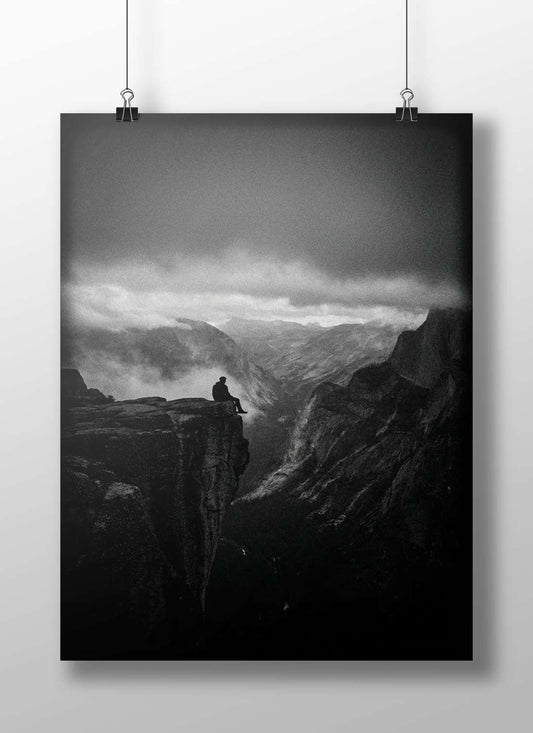 A solitary man seated on a rocky cliff edge overlooking a mountainous valley Main Subject: A solitary man seated on a rocky