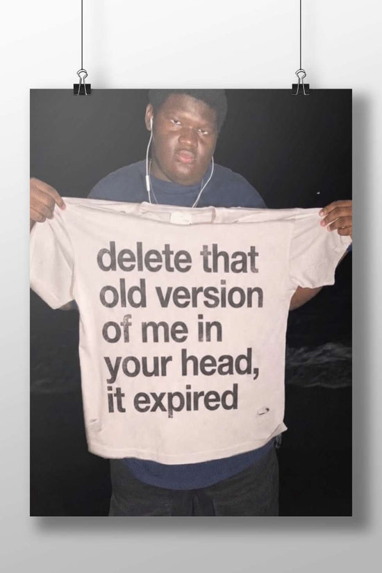 The phrase "delete that old version of me in your head, it expired" printed on a T-shirt. Main Subject: The phrase "delete
