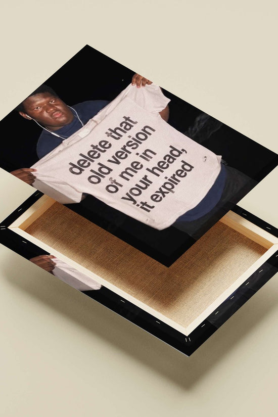 The phrase "delete that old version of me in your head, it expired" printed on a T-shirt. Main Subject: The phrase "delete