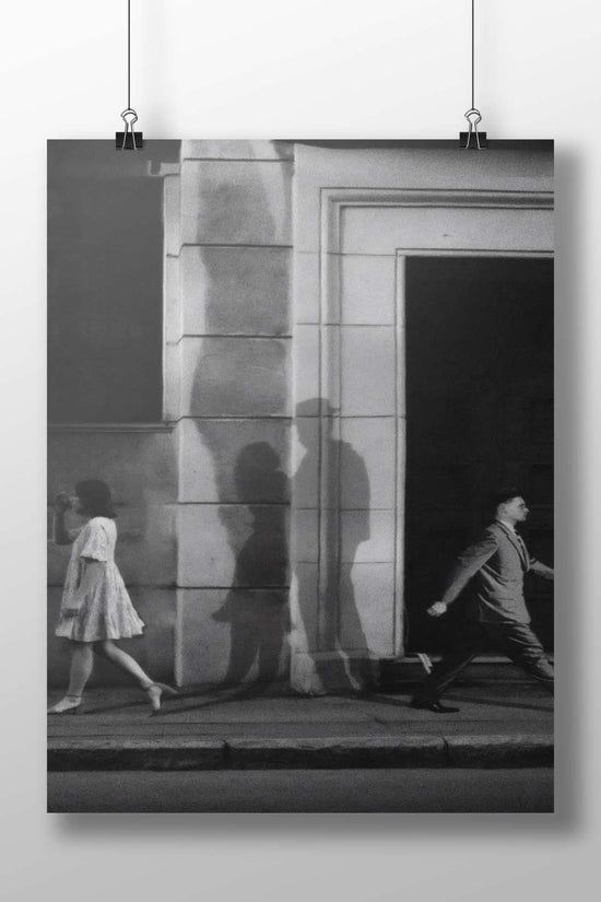 Two pedestrians (a woman in a dress and a man in a suit) walking past