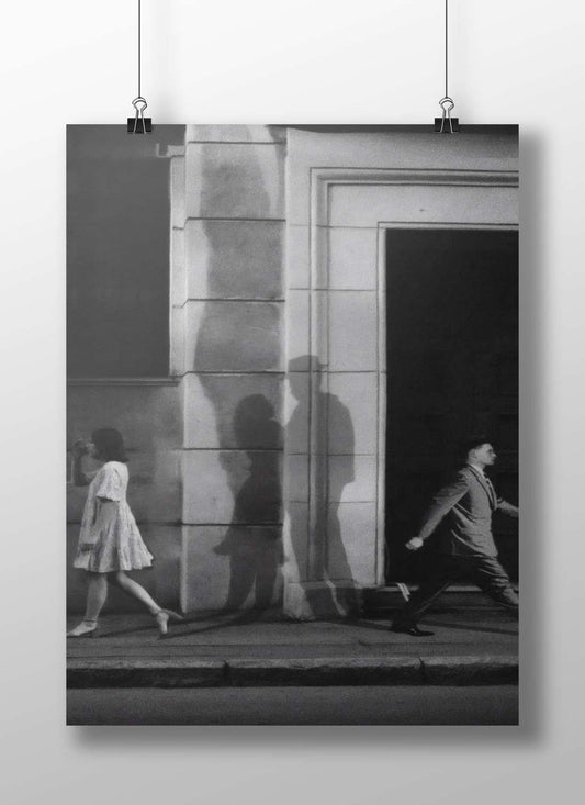 Two pedestrians (a woman in a dress and a man in a suit) walking past
